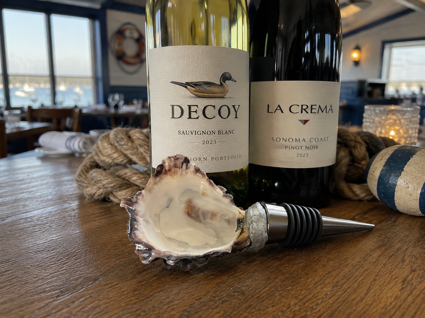 Pearlescent oyster shell wine topper beside wine bottles